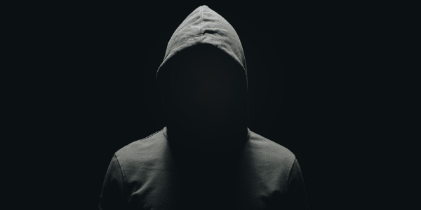 Faceless hacker hiding in the dark